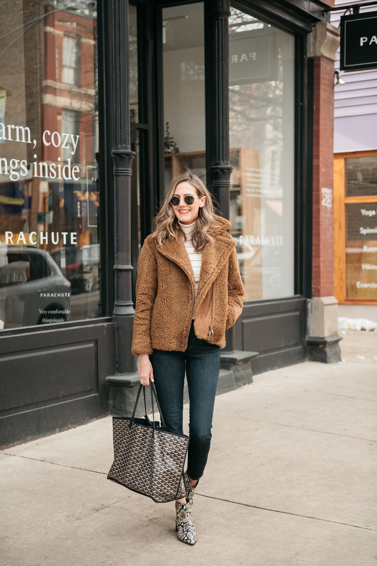 woman smiling and wearing brown jacket, jeans, and bag and sharing In Defense of Hobbies