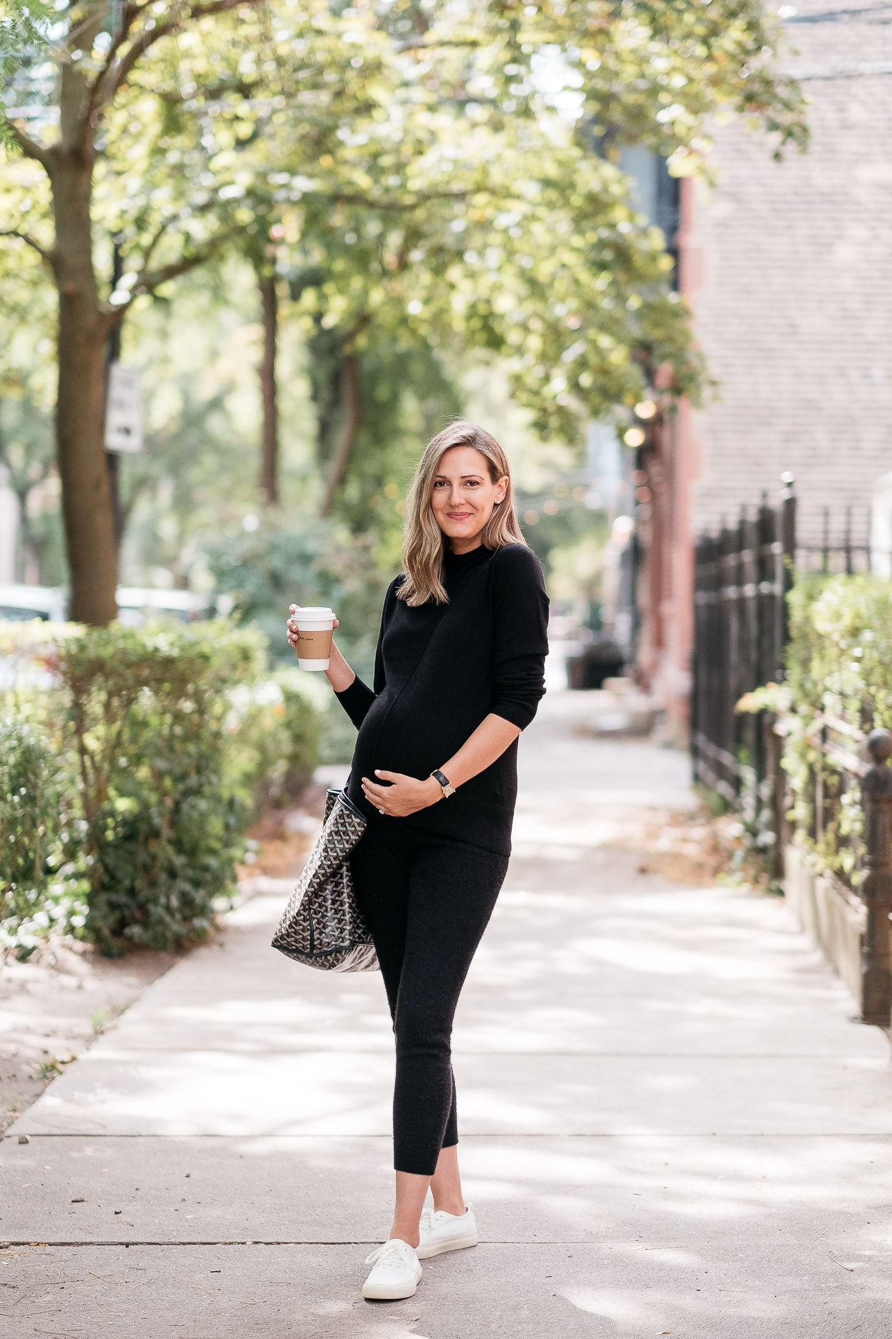 woman standing on the side walk and wearing all black outfit from Banana Republic and holding a drink