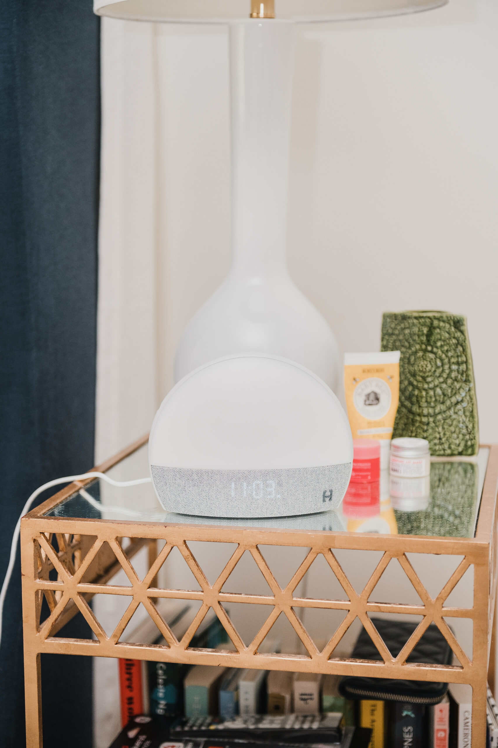 bedside table with Hatch Restore, lamp, skincare products, and books