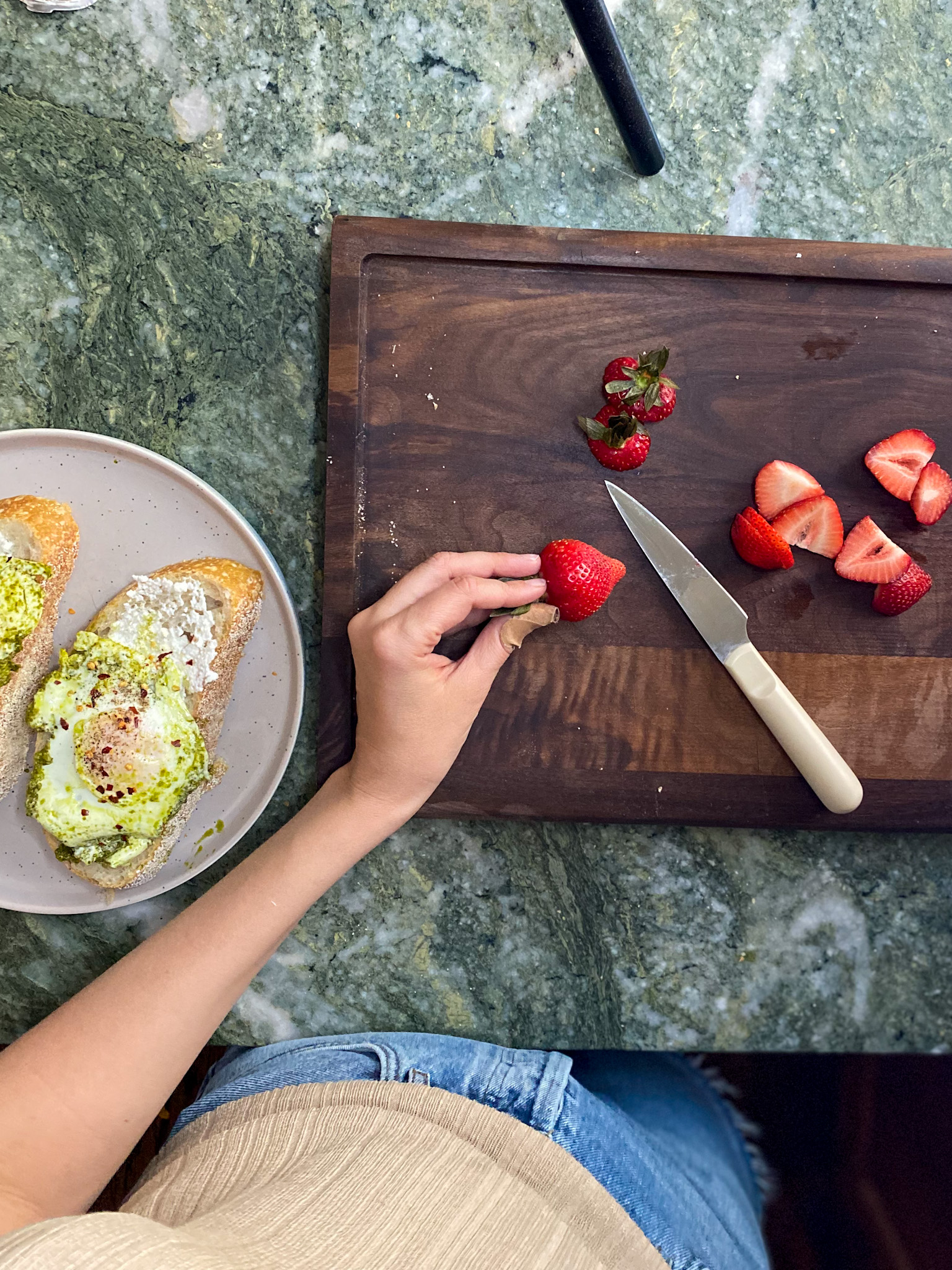 woman chopping strawberries on a wooden chop board