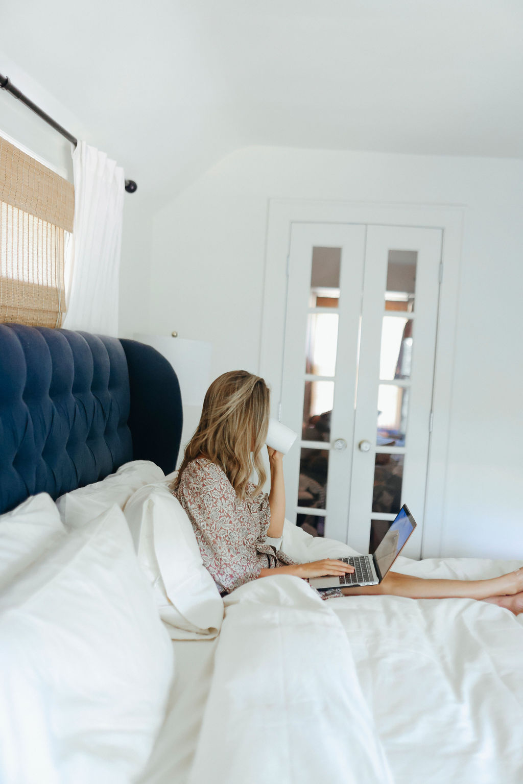 woman using her laptop on a bed with linens from Brooklinen LDW Sale