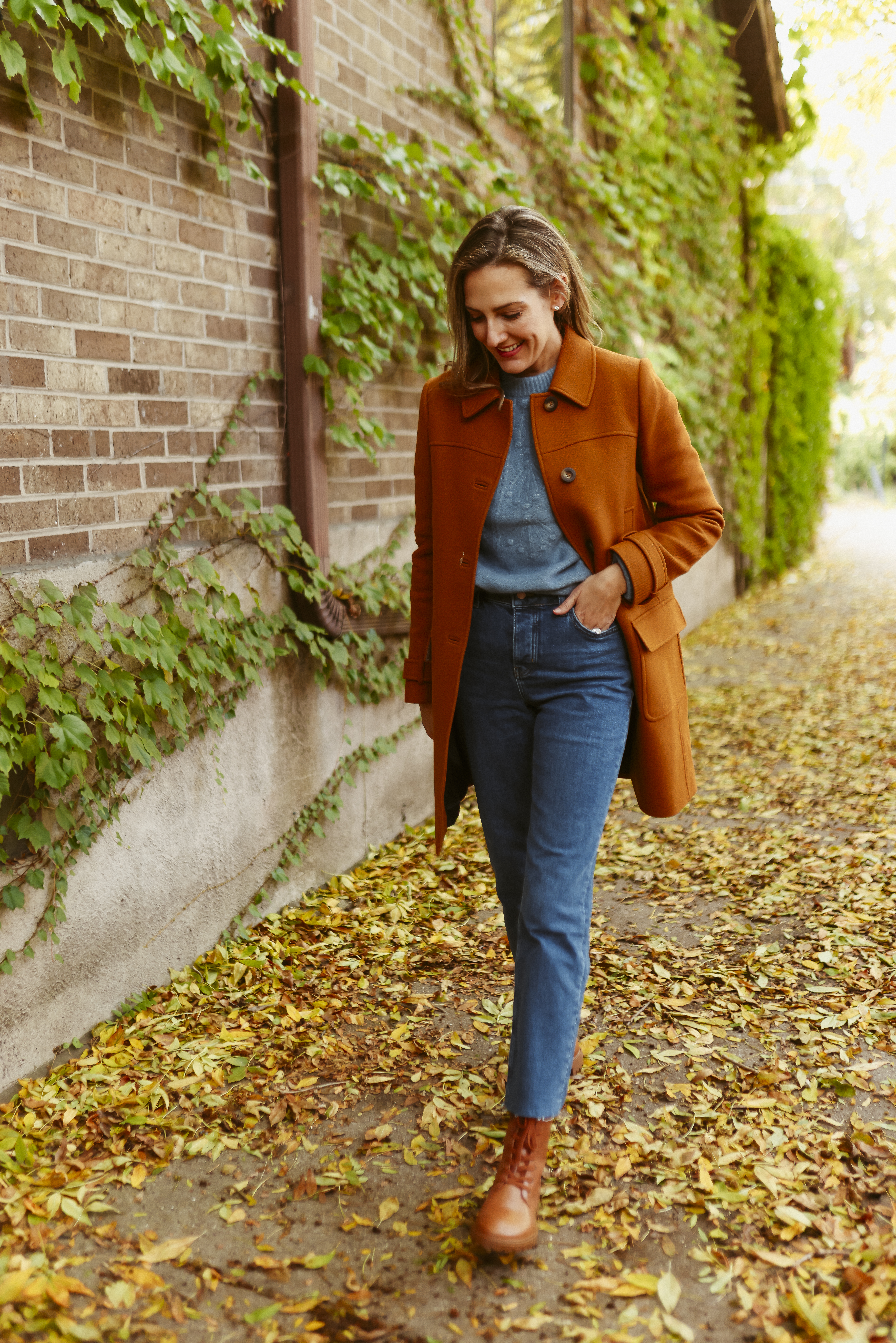 woman in jeans, blue sweater, and brown jacket for Holiday Style with Boden