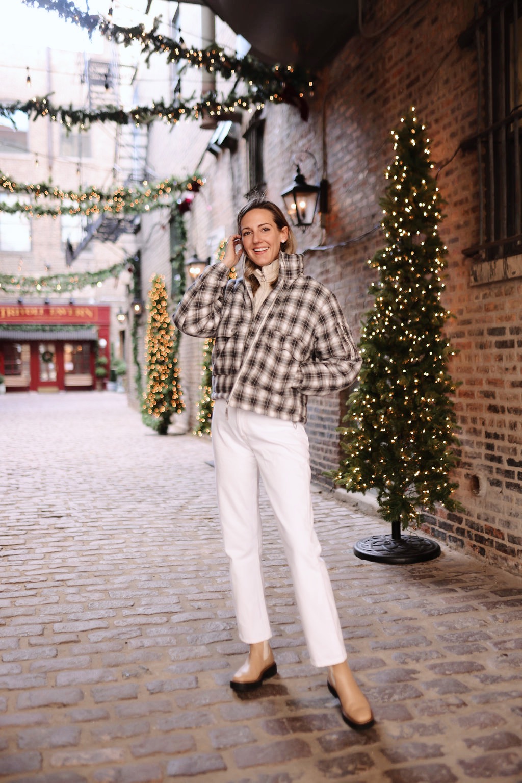 woman standing and wearing sweater and white pants sharing Holiday Gifting with Urban Outfitters