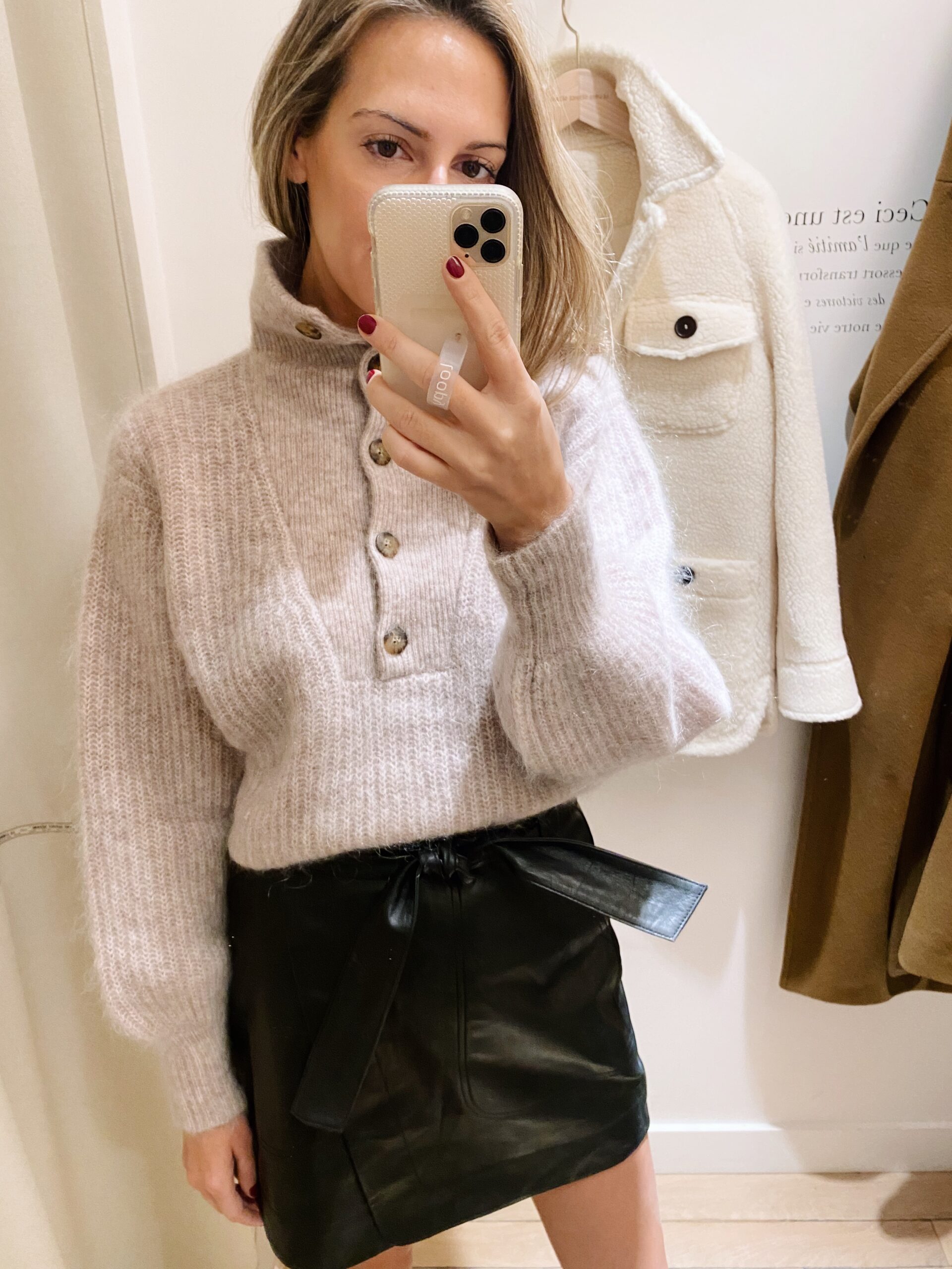 woman trying on grey coat and leather skirt from Sézane Paris Picks