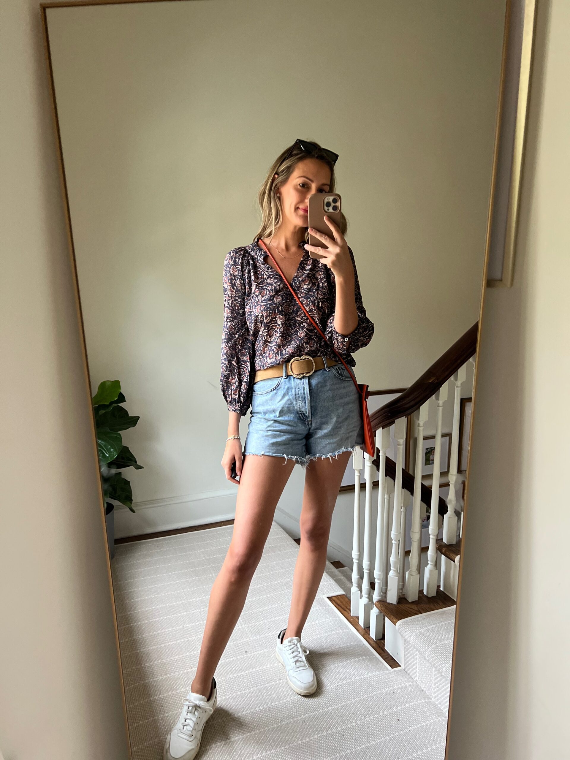 woman taking a selfie and showing her Real Outfit Recap wearing denim pants and printed top