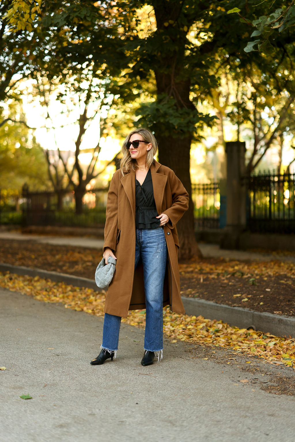woman wearing black top, denim jeans, and coat