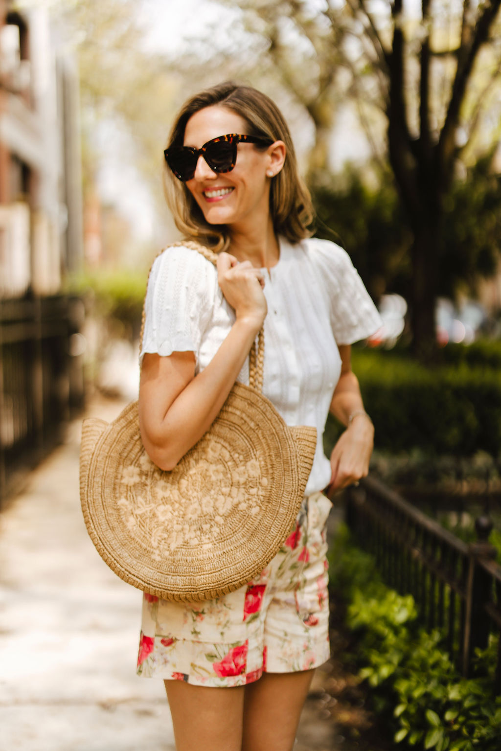 for Classic Style with Sézane woman wears white top, floral shorts, and weaved bag